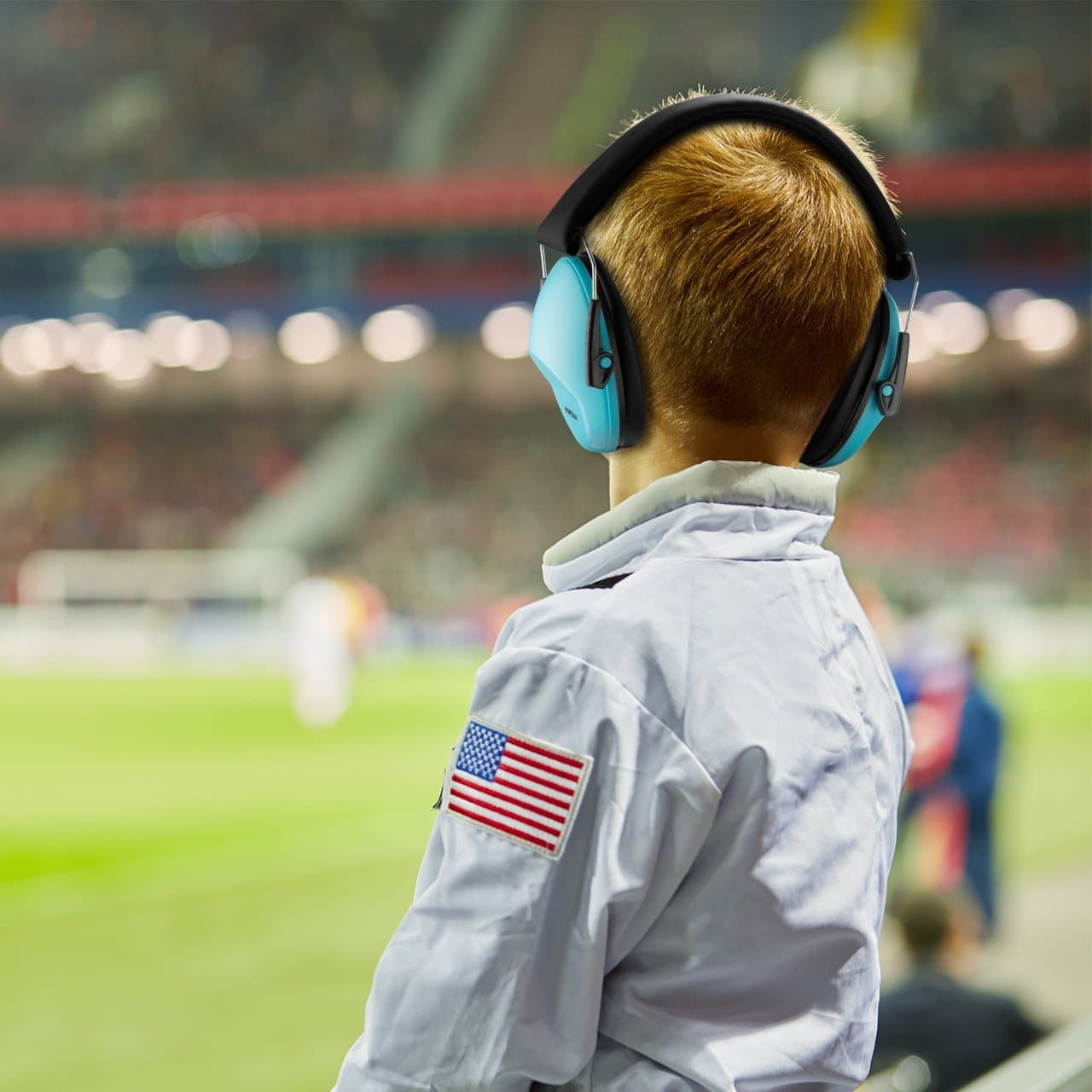 Child wearing ear defenders watching a sports match