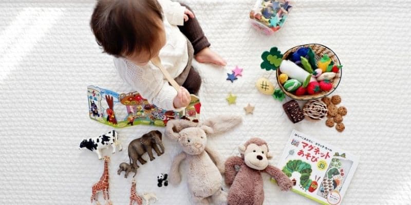 Baby sitting on a cloth playmat surrounded by their toys